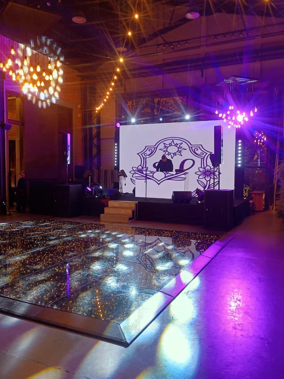 Pista de dança com luz roxa e dourada e logo do cliente no palco