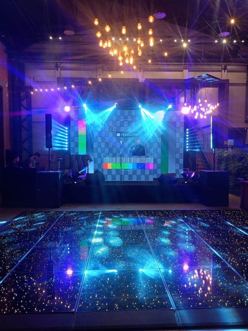 Palco com iluminação colorida e telão para DJ